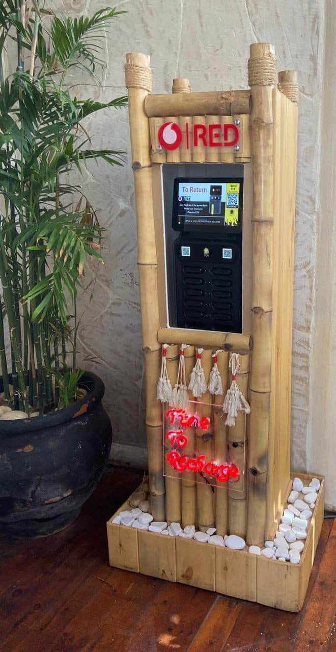 A bamboo charging station on a wooden floor indoors, its screen showing return instructions